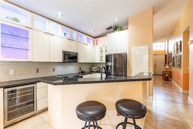 kitchen with backsplash, a kitchen breakfast bar, wine cooler, white cabinetry, and stainless steel appliances