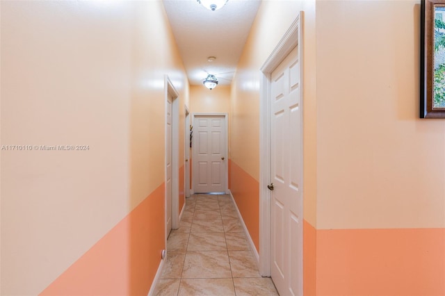 hallway featuring light tile patterned floors and a textured ceiling