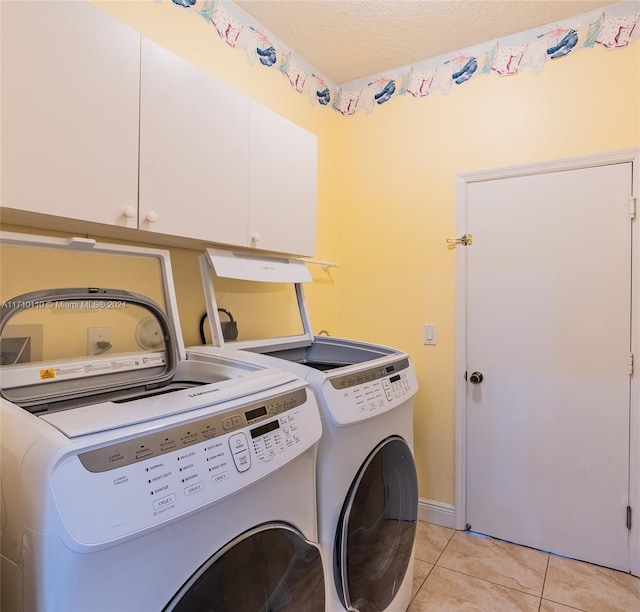 washroom featuring cabinets, independent washer and dryer, a textured ceiling, and light tile patterned floors