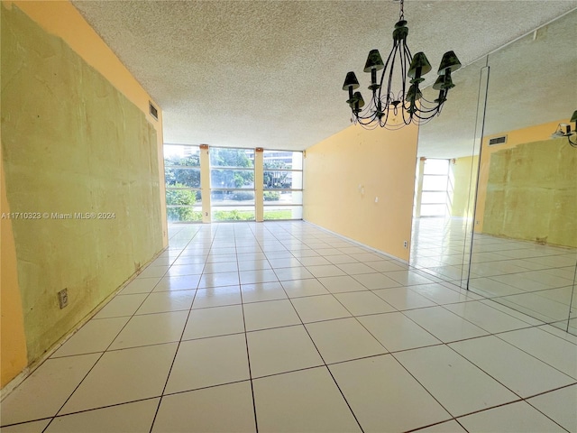 unfurnished room featuring plenty of natural light, a chandelier, a textured ceiling, and a wall of windows