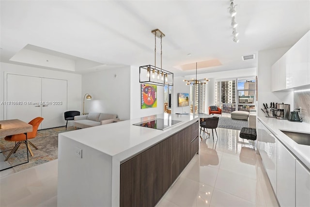 kitchen featuring white cabinets, dark brown cabinetry, black electric cooktop, and a tray ceiling