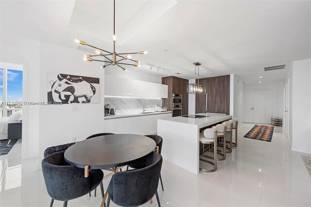 dining area featuring a notable chandelier, light tile patterned floors, and sink