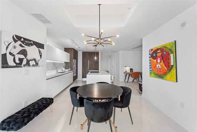 dining space with sink, light tile patterned floors, and a notable chandelier