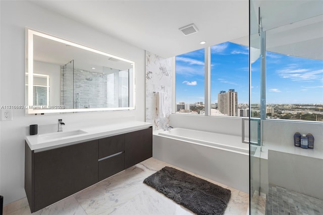 bathroom with vanity and shower with separate bathtub