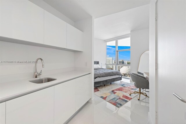 bedroom featuring light tile patterned flooring, floor to ceiling windows, and sink