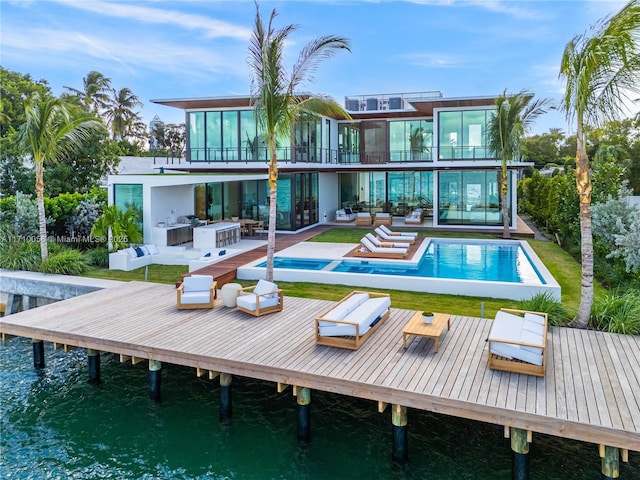 rear view of property with an outdoor kitchen, an outdoor hangout area, a balcony, a water view, and a patio