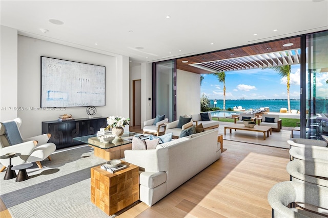 living room with floor to ceiling windows, a water view, and light wood-type flooring