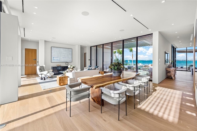 dining space with a water view, light hardwood / wood-style flooring, and floor to ceiling windows