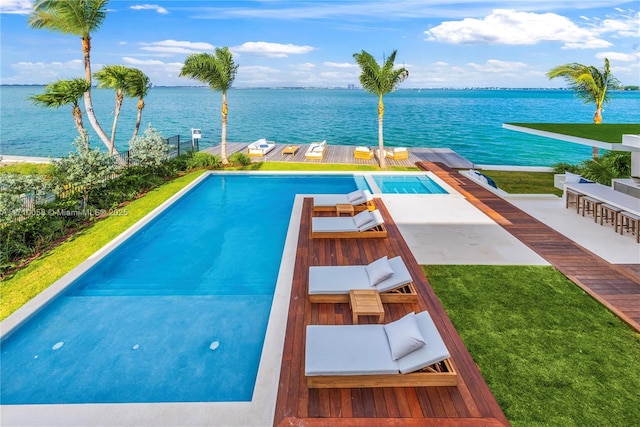 view of swimming pool featuring a bar, a yard, and a water view