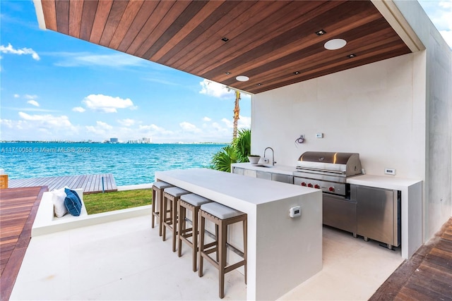 view of patio with grilling area, area for grilling, a water view, and a wet bar