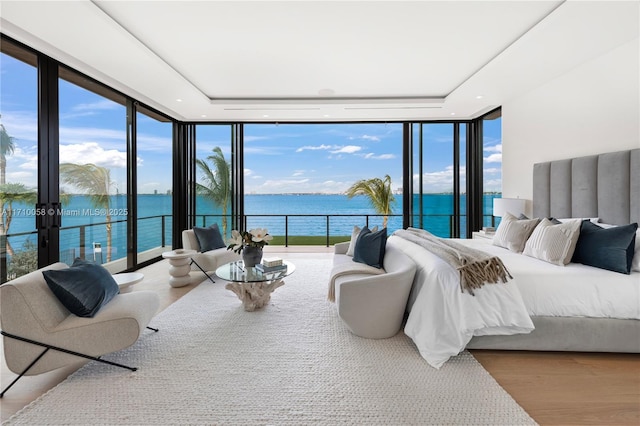 bedroom with a water view, light hardwood / wood-style flooring, and multiple windows