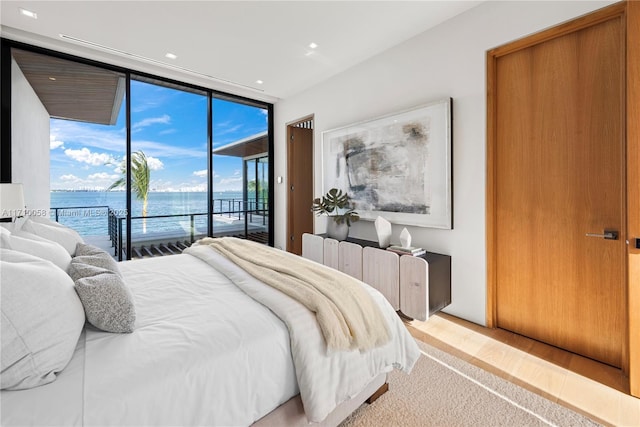 bedroom with access to outside, a wall of windows, a water view, and radiator