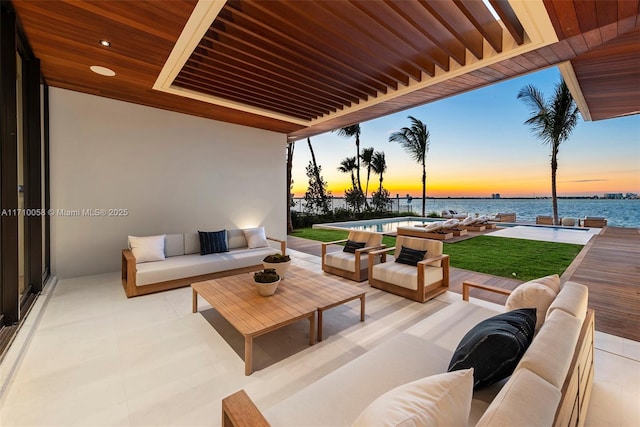 patio terrace at dusk with an outdoor hangout area and a water view