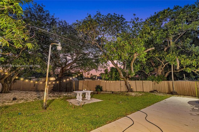 yard at dusk with a patio and a fenced backyard