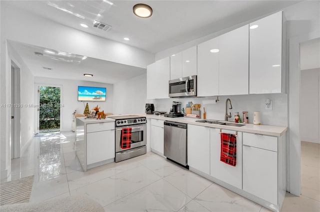 kitchen with kitchen peninsula, stainless steel appliances, white cabinetry, and sink