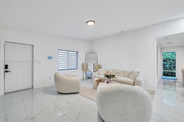 living area with baseboards and marble finish floor
