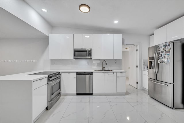 kitchen with modern cabinets, a peninsula, light countertops, a sink, and stainless steel appliances