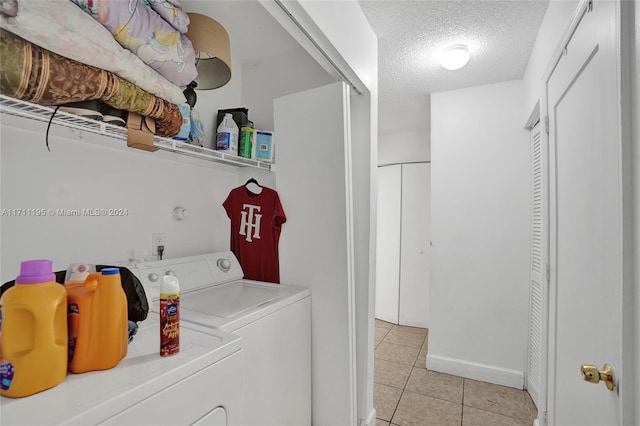 clothes washing area featuring washer and dryer, light tile patterned floors, and a textured ceiling