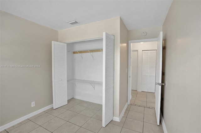 unfurnished bedroom featuring light tile patterned floors and a closet