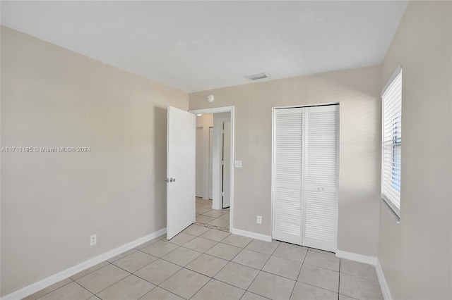 unfurnished bedroom featuring multiple windows, a closet, and light tile patterned floors