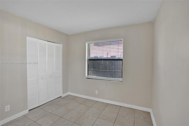 unfurnished bedroom with a closet and light tile patterned floors