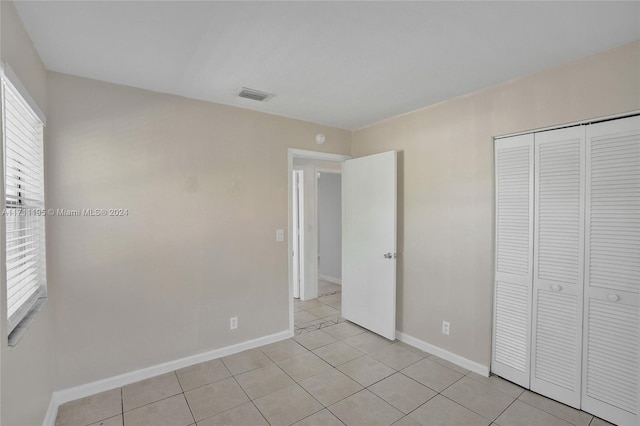 unfurnished bedroom with light tile patterned floors and a closet