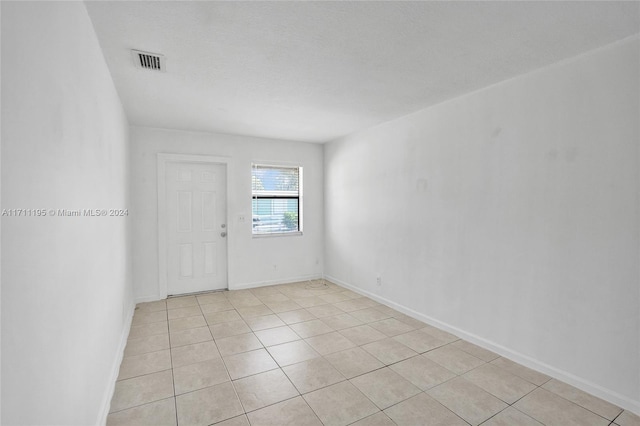 unfurnished room with light tile patterned floors and a textured ceiling