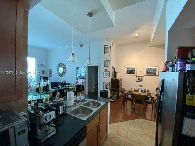 kitchen with pendant lighting, sink, stainless steel refrigerator, and light hardwood / wood-style flooring