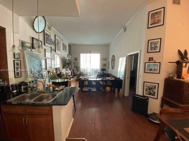 kitchen featuring dark hardwood / wood-style flooring, ornamental molding, sink, and hanging light fixtures