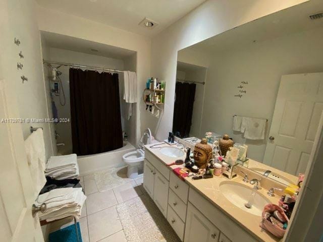 full bathroom with tile patterned floors, shower / bath combo with shower curtain, vanity, and toilet