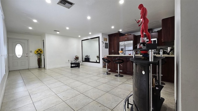 kitchen featuring stainless steel fridge with ice dispenser, light tile patterned floors, a kitchen breakfast bar, and a center island