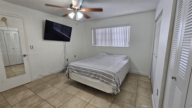 tiled bedroom with ceiling fan and a textured ceiling