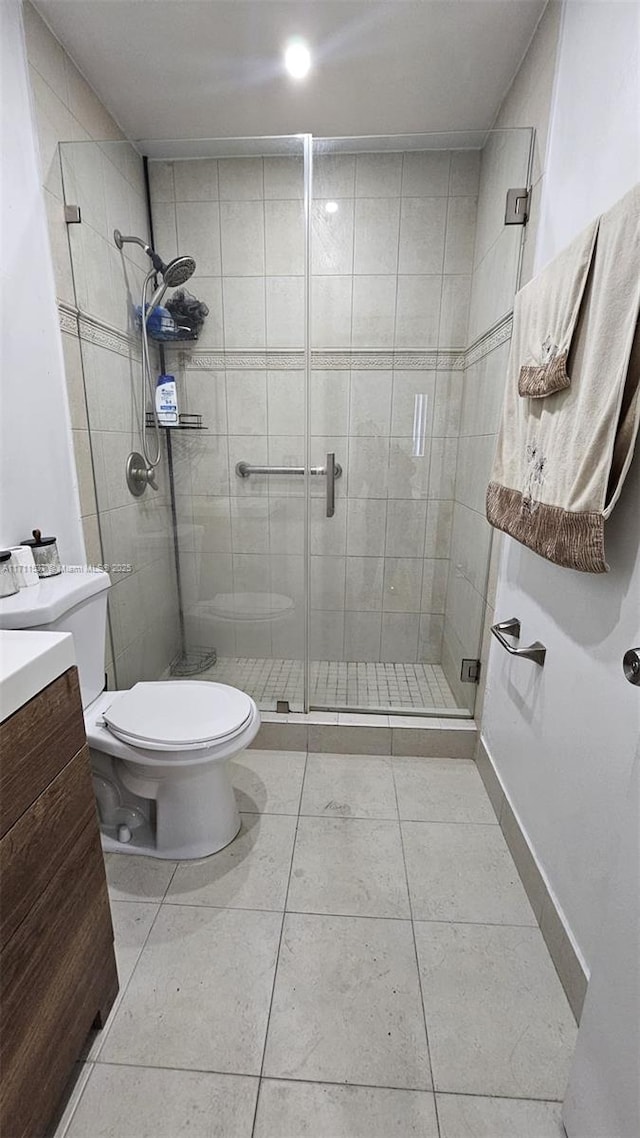 bathroom featuring a shower with door, tile patterned flooring, vanity, and toilet