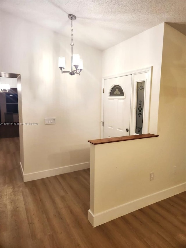 foyer with a textured ceiling, dark hardwood / wood-style floors, and a notable chandelier