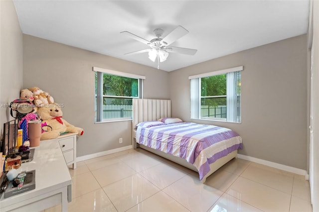 tiled bedroom featuring ceiling fan and multiple windows