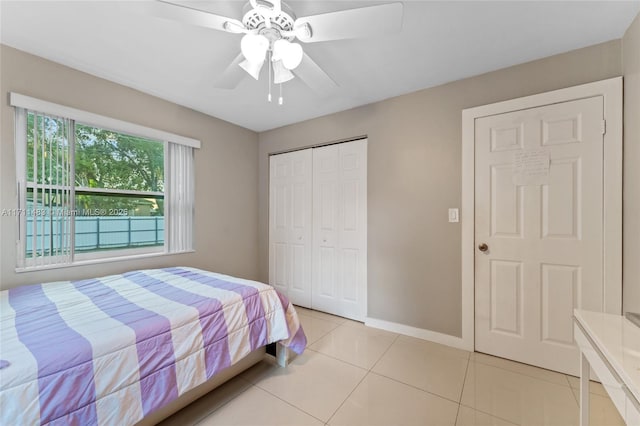 bedroom featuring ceiling fan, light tile patterned floors, and a closet