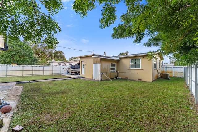 back of property with central AC unit and a lawn