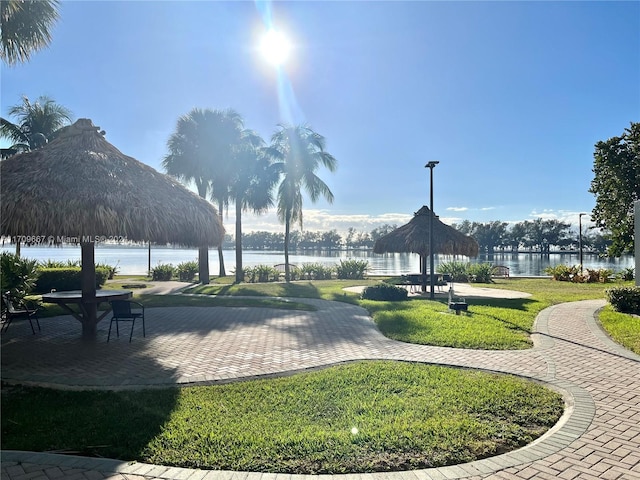 view of property's community with a gazebo, a lawn, a water view, and a patio