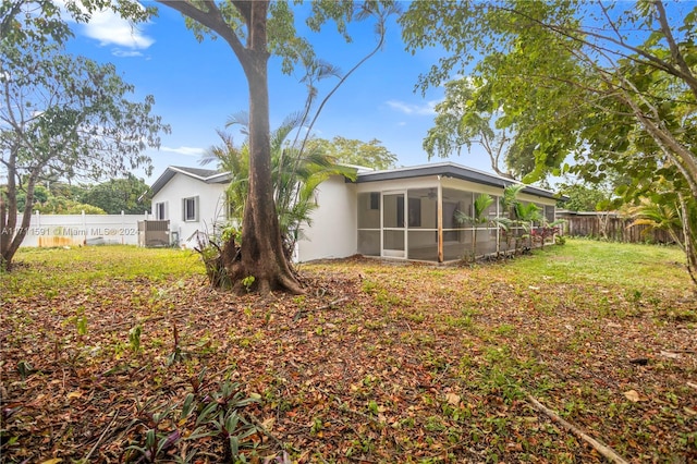 back of house featuring a lawn and a sunroom