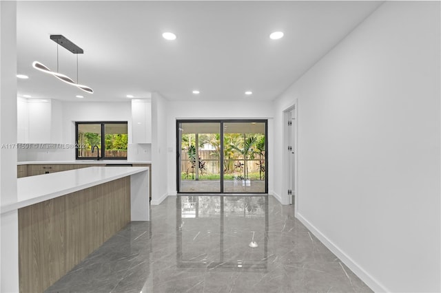 kitchen with a healthy amount of sunlight, white cabinetry, sink, and hanging light fixtures