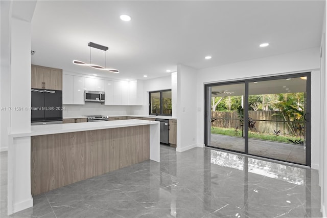 kitchen with decorative light fixtures, stainless steel appliances, white cabinetry, and sink