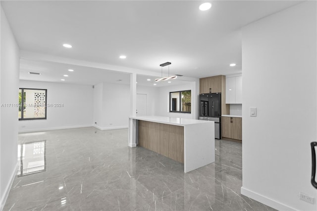 kitchen featuring white cabinetry, black refrigerator, a center island, and pendant lighting