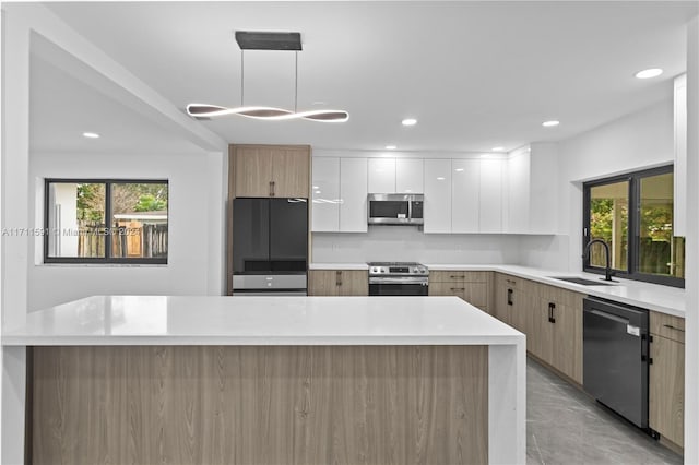 kitchen with a healthy amount of sunlight, white cabinetry, stainless steel appliances, and hanging light fixtures