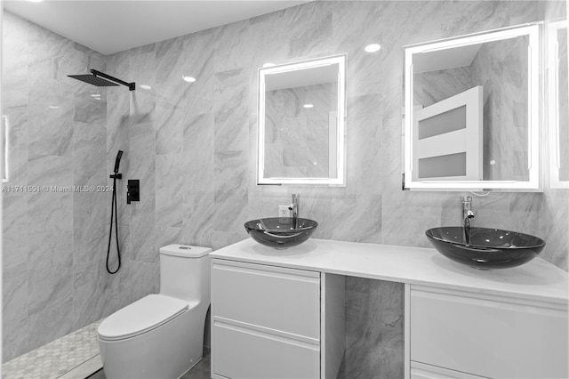 bathroom featuring a tile shower, vanity, and tile walls