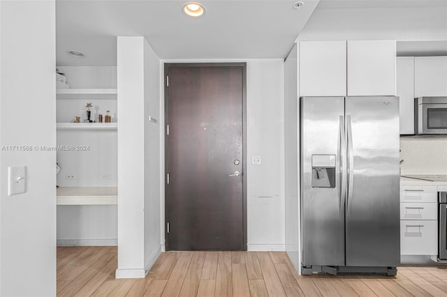 kitchen with white cabinets, appliances with stainless steel finishes, and light hardwood / wood-style floors