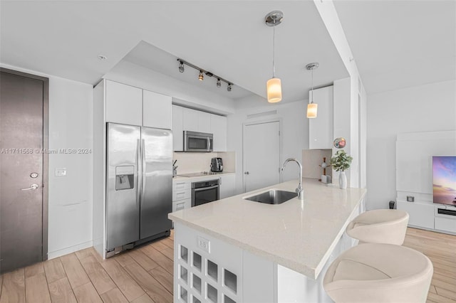 kitchen with white cabinetry, sink, light hardwood / wood-style floors, and appliances with stainless steel finishes