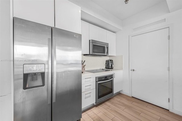 kitchen featuring tasteful backsplash, white cabinets, stainless steel appliances, and light hardwood / wood-style floors