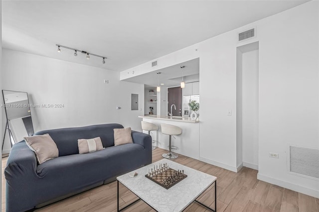 living room featuring light wood-type flooring, sink, and electric panel