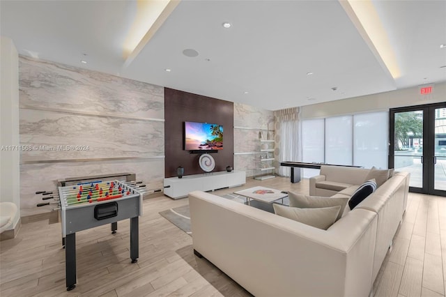 living room with french doors, light hardwood / wood-style floors, and tile walls