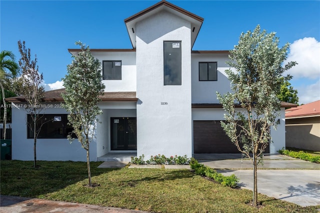 contemporary house with a garage, driveway, a front lawn, and stucco siding